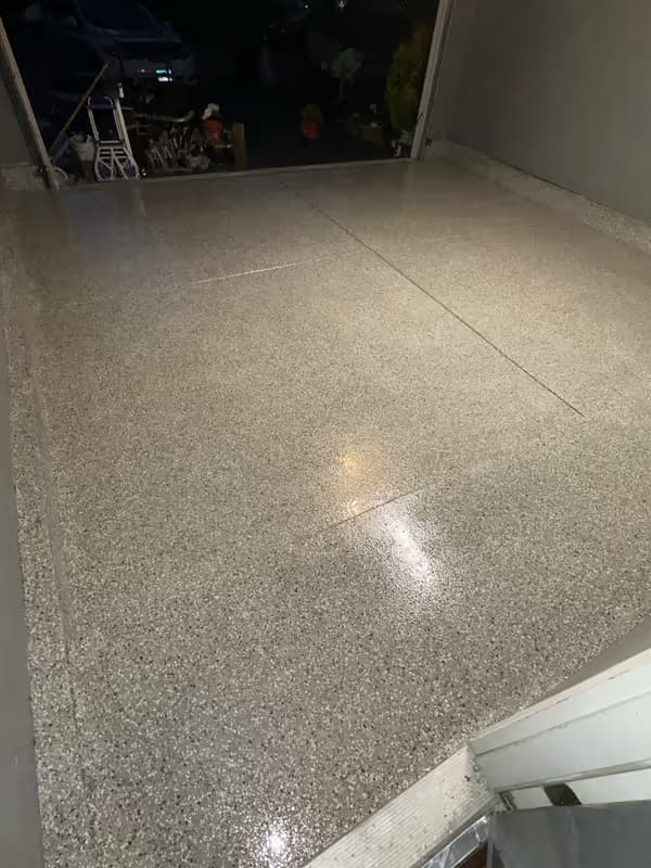 Gray flake epoxy garage floor with crisp coving line at the wall — residential install
