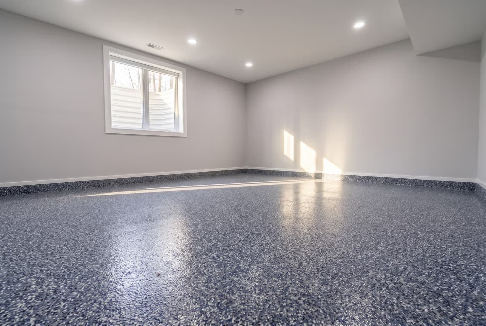 Slate-blue and charcoal flake epoxy floor in an empty basement room