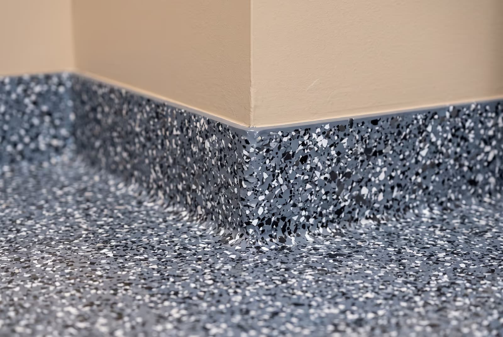 Flake epoxy floor meeting a 4-inch cove base at the garage wall