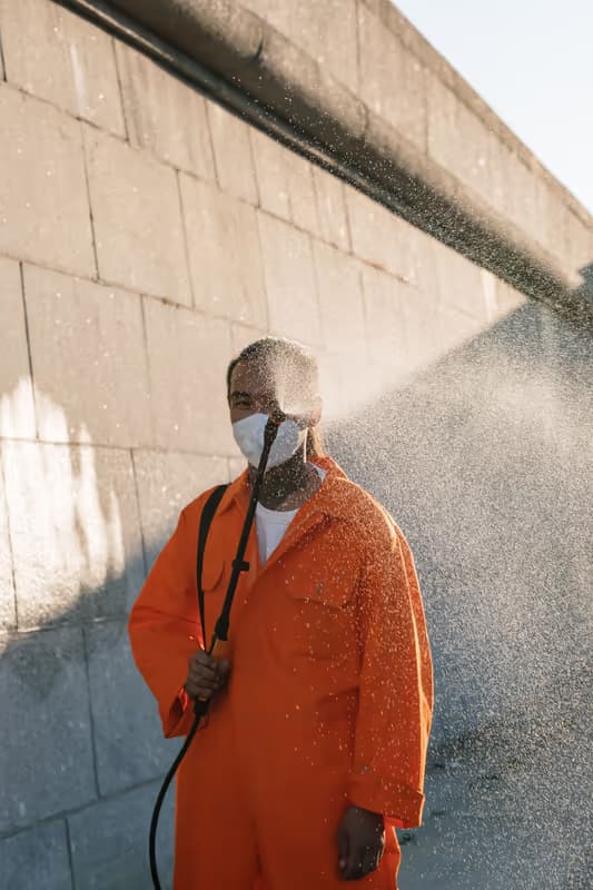 Pressure washing a large stone-block wall — spray backlit against the building exterior