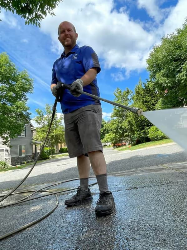 Pressure washing a residential concrete driveway — wide spray fan on the wand